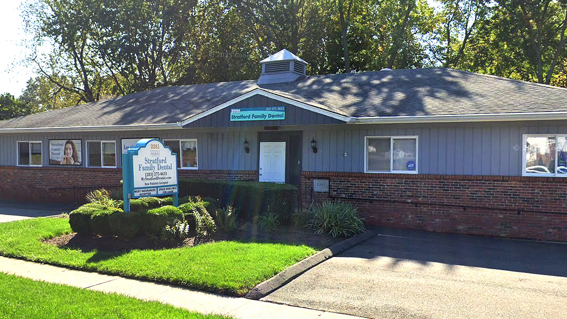 The image shows a single-story building with a peaked roof and a sign indicating it s a church. There are two visible doors, one on each side of the entrance area, and a parking lot in front of the building. The sky is clear, suggesting it might be a sunny day.