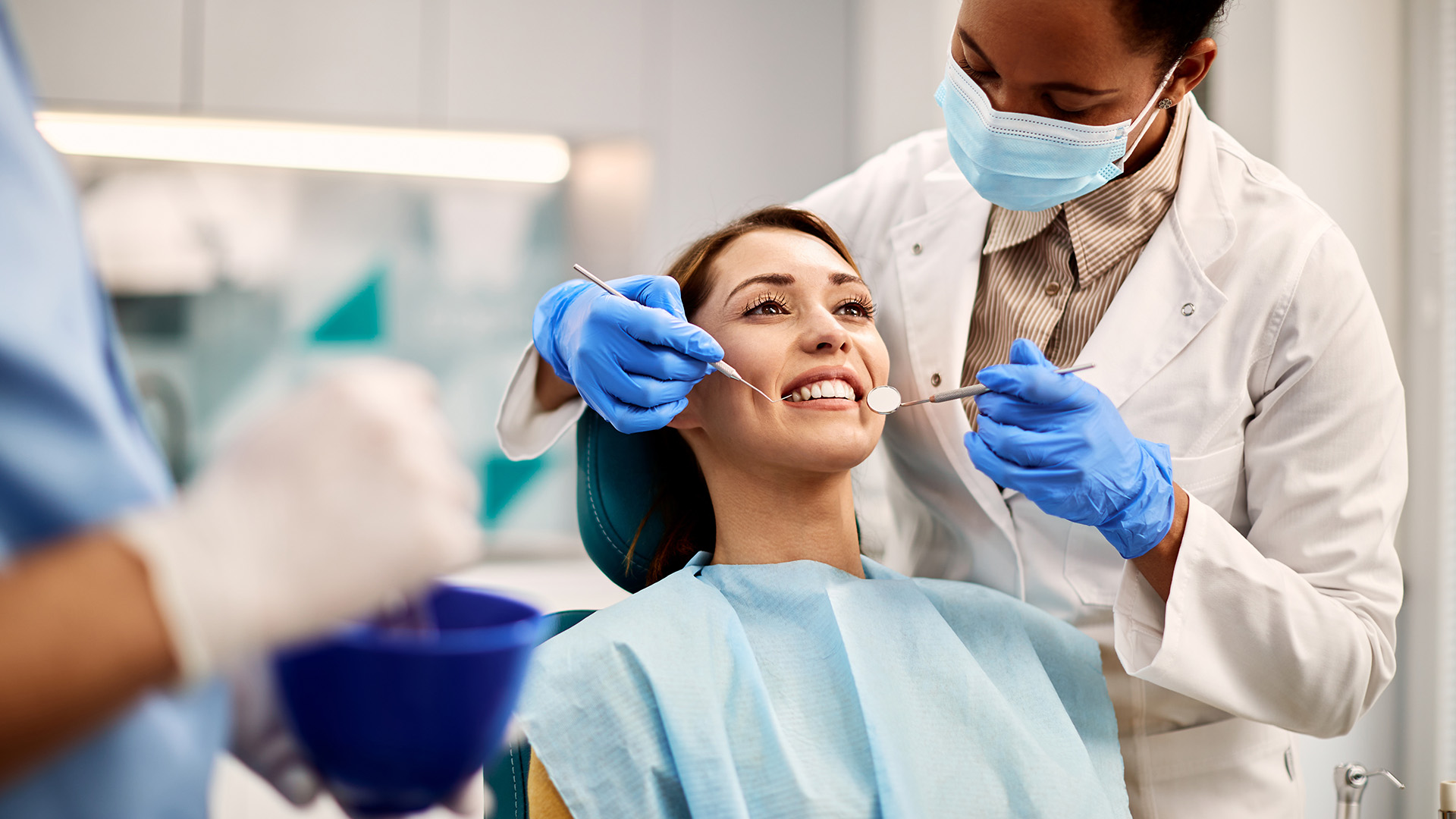 The image shows dental professionals performing dental procedures on a patient, with a focus on teeth whitening, set in a clinical environment.