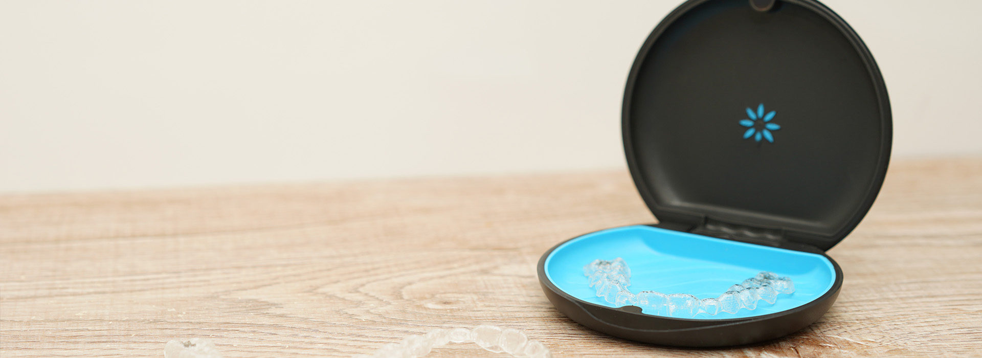 The image shows a black electronic device with a blue light and a small circular object next to it on a white surface.