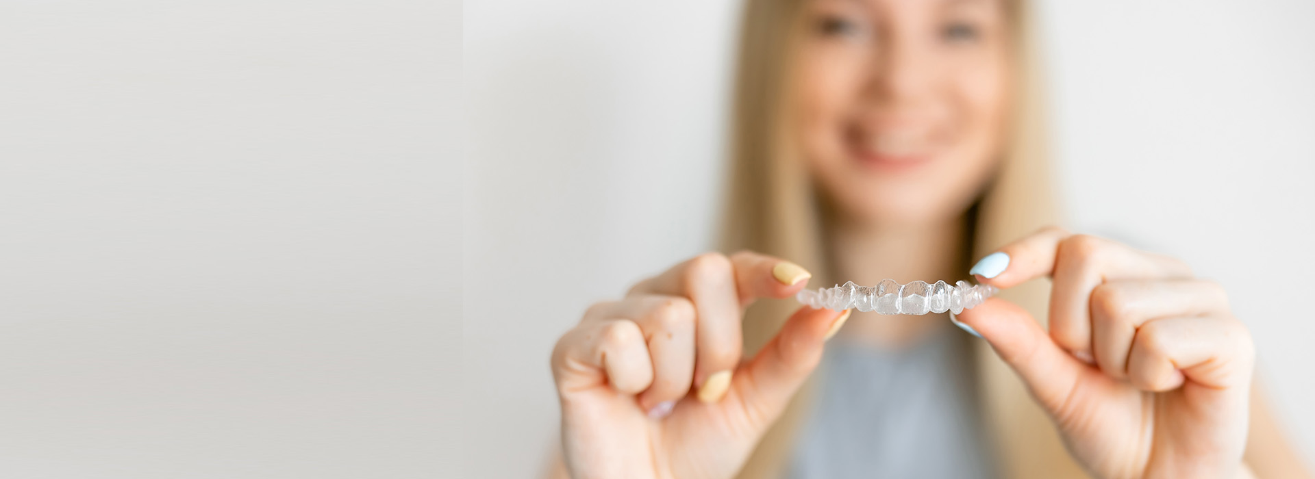 A woman holding up a small object between her fingers with a blurred background.