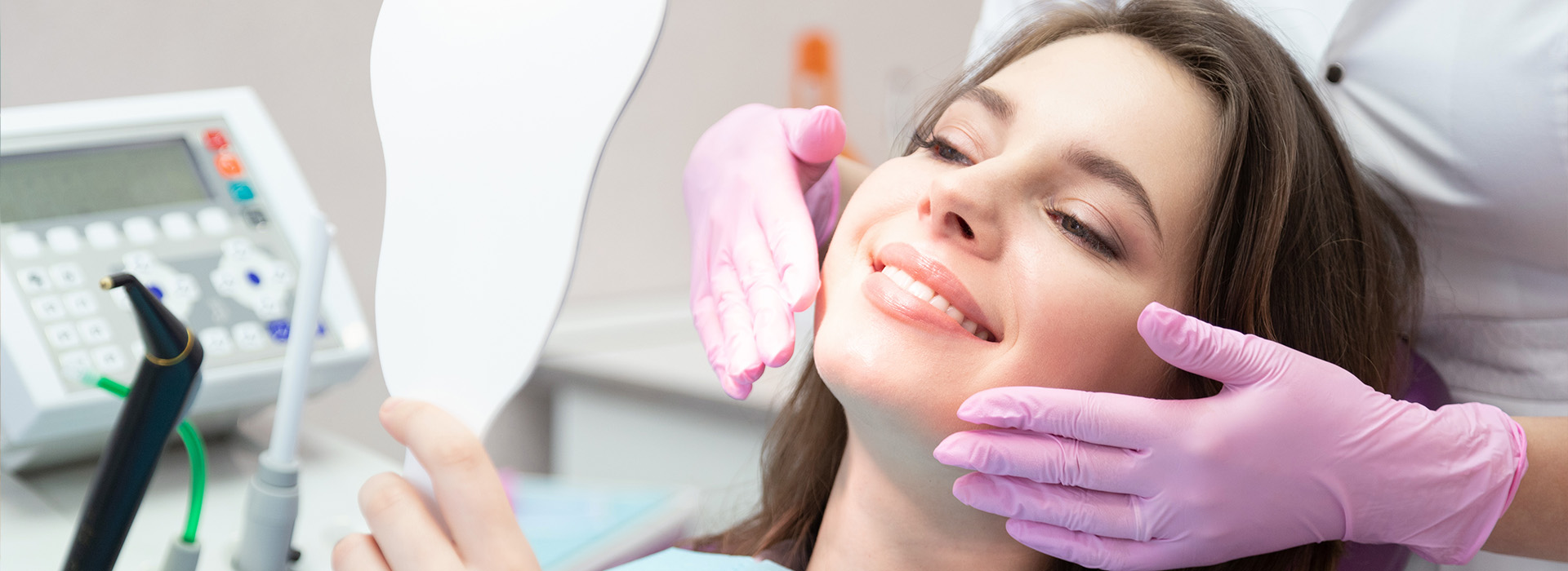 A woman receiving dental treatment with a professional standing behind her.