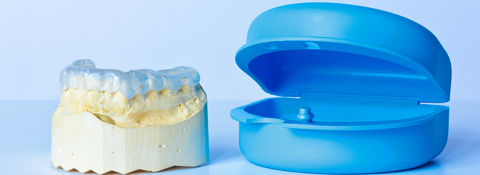 The image shows two dental implants, one with a blue protective cap and the other without, placed on a white background.
