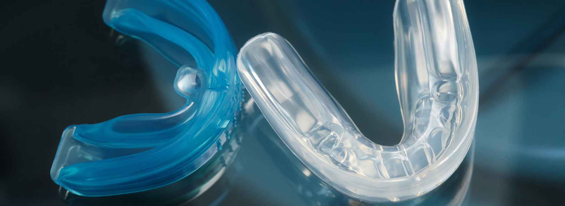 This is a close-up photograph of a blue plastic object with a clear transparent element, possibly a toothbrush head, against a blurred background.